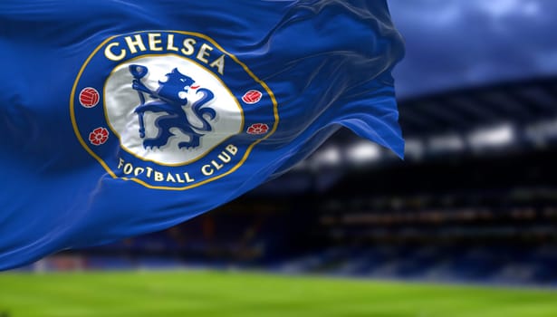 London, UK, May 2022: The flag of Chelsea Football Club waving inside the Stamford Bridge stadium at night. Chelsea F.C. is a professional football club based in Fulham, London