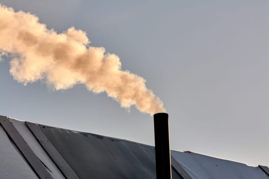 smoke is coming from the chimney of the bourgeoisie. the stove is being heated. High quality photo