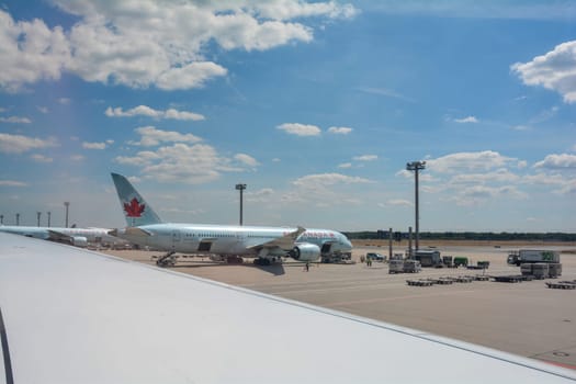 Frankfurt Airport Germany August 02, 2022 - View from the aircraft window onto a wing and a view of an Air Canada machine being loaded