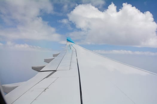 View from an airplane window showing the wing and sky with clouds