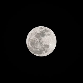 Beautiful soft white super full moon with details on the lunar surface in the dark night isolated on black sky background