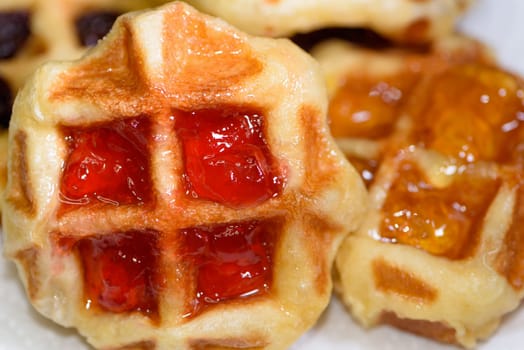 Close up of fresh waffles topped with delicious sweet strawberry jam and pineapple jam on top. Make homemade food or snacks at home