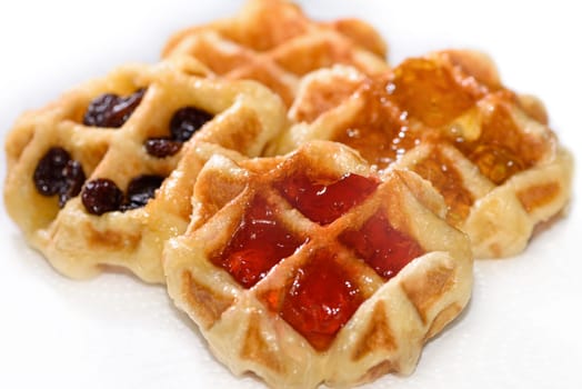 Close up many fresh waffles with above strawberry jam, pineapple jam, and dried raisins isolated on white background. Making homemade food or dessert at home
