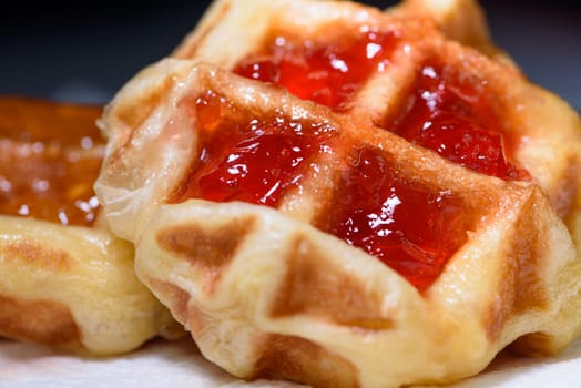 Close up of fresh waffles topped with delicious sweet strawberry jam and pineapple jam on top. Making homemade food or dessert at home
