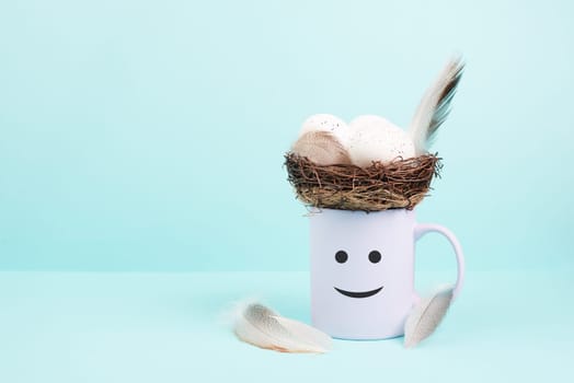 Cup with an easter egg nest, bird feathers and a smiling happy face, spring holiday greeting card