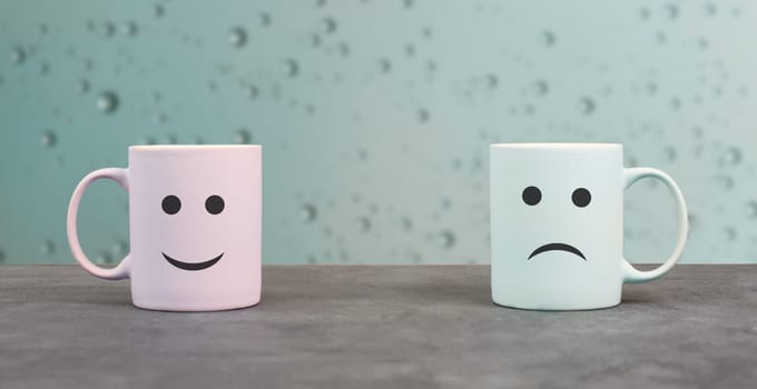 Happy and sad face, cups on a window sill, hot drink on a rainy day, relationship and friendship concept