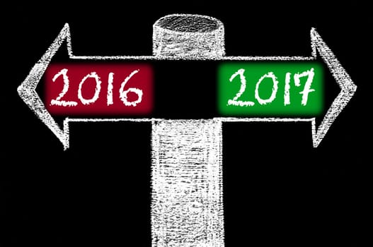 Opposite arrows with Year 2016 versus Year 2017. Hand drawing with chalk on blackboard. Choice conceptual image