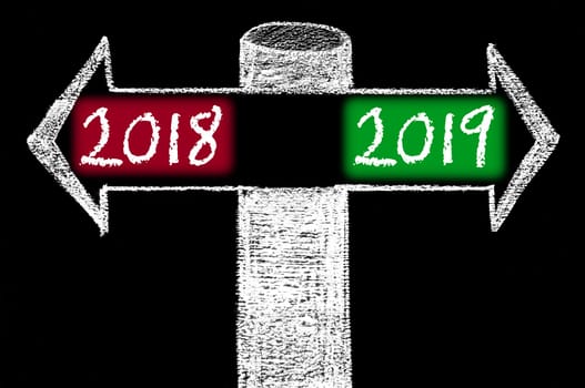 Opposite arrows with Year 2018 versus Year 2019. Hand drawing with chalk on blackboard. Choice conceptual image