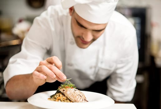 Male chef garnishing his dish, ready to serve