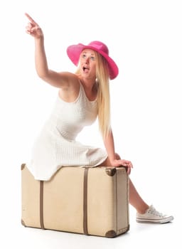Woman sits on suitcase and points to something
