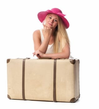 Young woman with straw hat leans on a suitcase