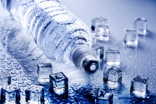 Fresh drinking mineral water in plastic bottle with ice cubes and iced drops. Healthy living concept.