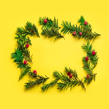 Christmas holiday frame background. Christmas tree with red decor over pastel yellow background. Top view. Merry christmas and happy new year for 2019.