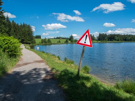 Road sign at the edge of the Pond Koegel in summer with a blue sky and small white clouds.