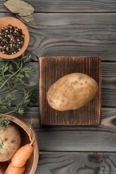 Big yellow potato on kitchen wooden board. Flat lay view. Fresh raw unpeeled potato. Prepare ingredients for cooking. Traditional cuisine, recipe, healthy food. Vegetables and flavorings.