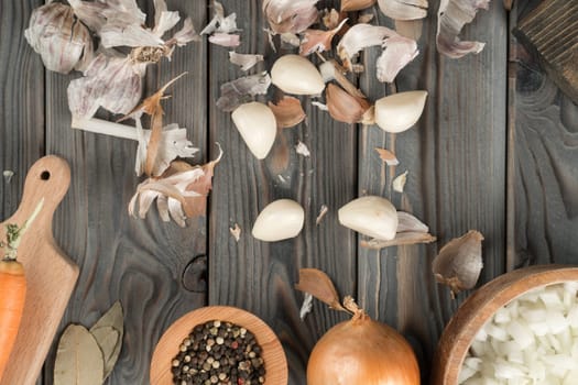 Peeling of spicy white garlic. Scatter garlic and dry peel across kitchen wooden table. Flat lay. Fragrant flavorings. Prepare ingredients for cooking, recipe. Healthy diet, food waste.