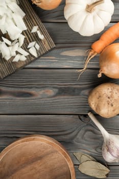 Cutting white spicy onion into cubes on kitchen wooden board. Empty bowl for diced onion. Flat lay view. Layout of fresh raw vegetables. Prepare ingredients for cooking. Healthy food.
