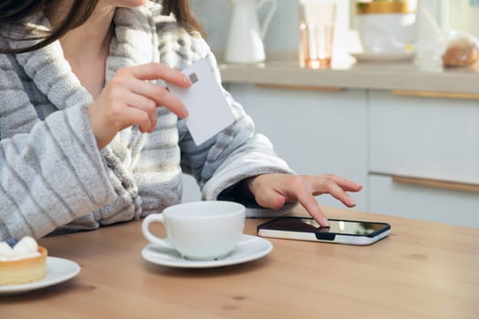 Woman using her debit card and smartphone to buy something online