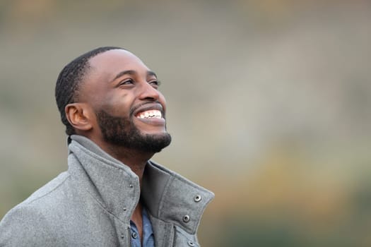 Happy black man laughing looking up in winter outdoors