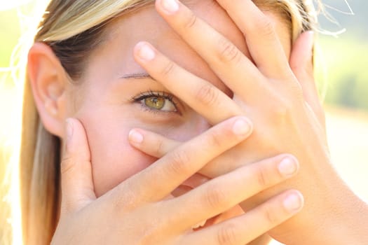 Front view portrait of a timid teen hiding behind her hands
