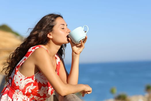Profile of a tourist on the beach drinking coffee