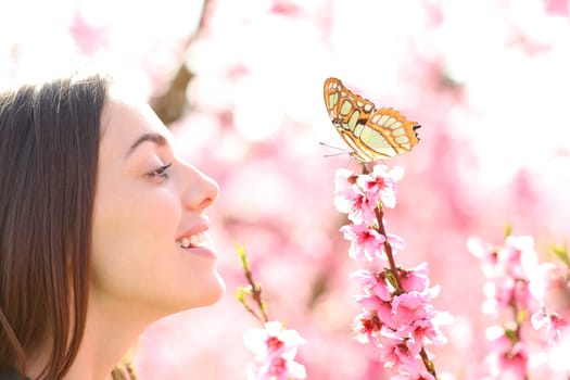 Profile of a happy woman lookijng at butterfly in a field