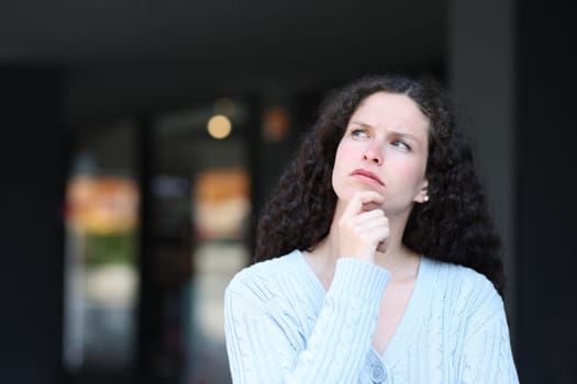 Serious pensive woman in the street looking above