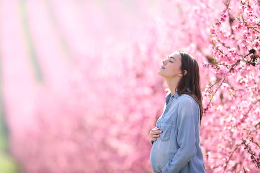 Side view of a pregnant woman breathing fresh air in a pink field
