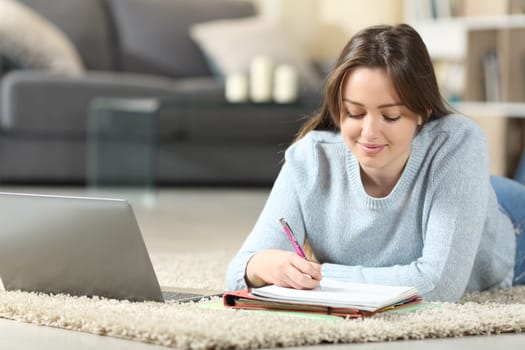 Teen studying lying on the floor taking notes at home