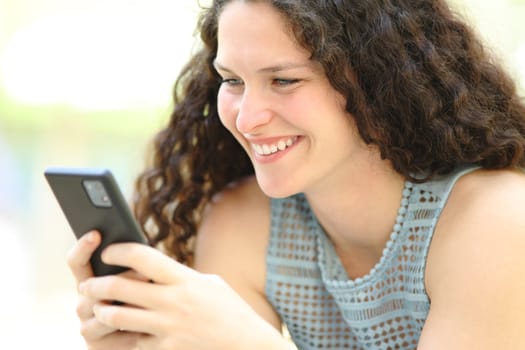 Happy woman using smart phone smiling outside