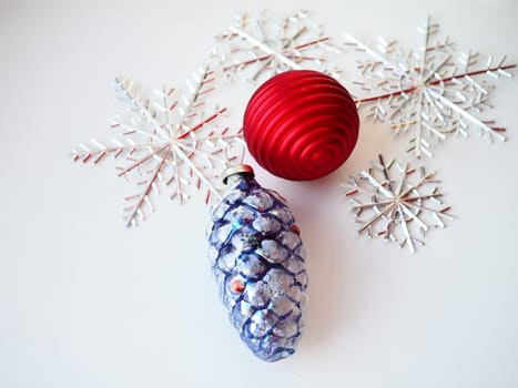 New Year and Christmas tree toys and decorations on a white background. A blue-violet glass cone with decorative white snow on top. Red striped Christmas ball. Silvery snowflakes