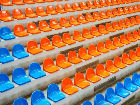 Bleachers, empty seats in the stands of the arena or auditorium. Rows of blue and orange stadium seats without spectators. The concept of the abolition of sports and mass entertainment events.