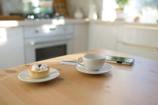 Kitchen table, credit card, cup of coffee or tea and smartphone