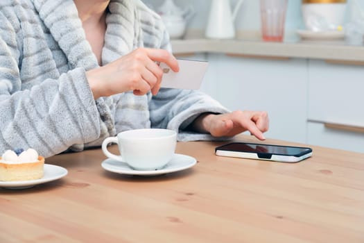 Woman using her debit card and smartphone to buy something online