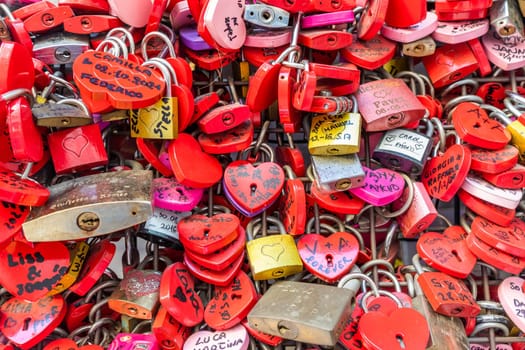 Verona, Italy - June 2022: background of heart-shaped locks on a wall, symbol of love forever
