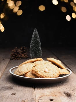 Tasty organic oat cookies on a rustic wooden table with Christmas lights bokeh