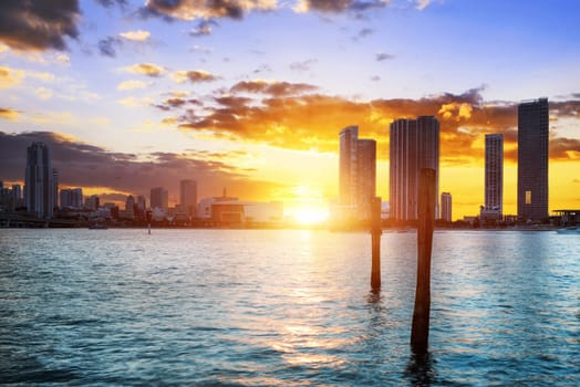 Miami city skyline panorama at dusk with urban skyscrapers over sea with reflection
