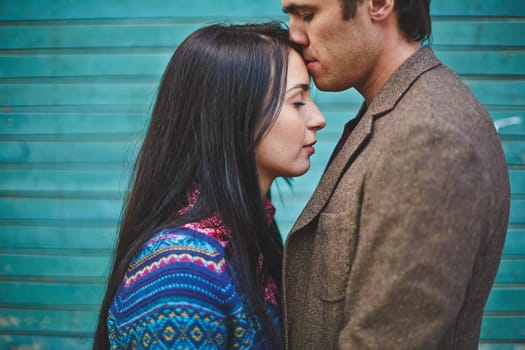 Amorous man kissing young woman on forehead