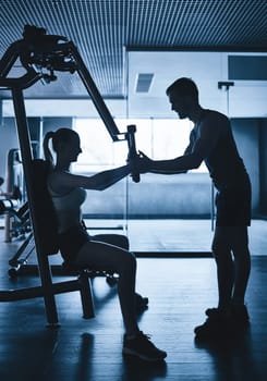 Outlines of trainer and sporty woman exercising on facilities