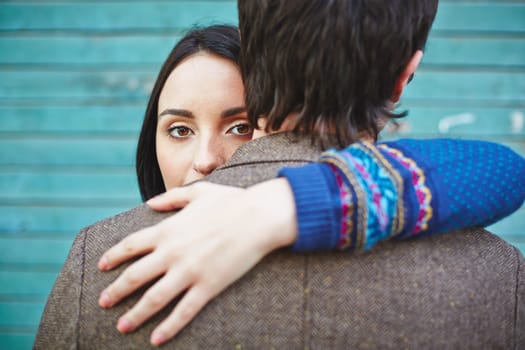 Young woman looking at camera out of man back while embracing him