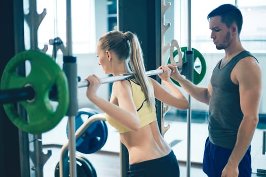 Trainer teaching young woman how to lift weight