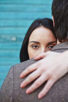 Pretty female looking at camera out of man back while embracing him