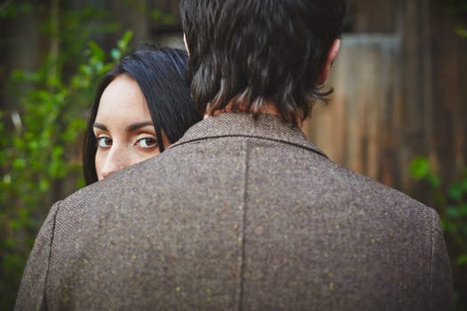 Young female looking at camera out of man shoulder