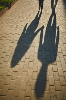Shadows of amorous dates walking down trottoire