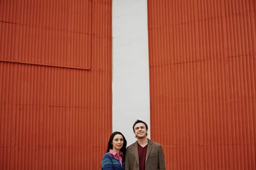 Young couple in casualwear standing by wall outside