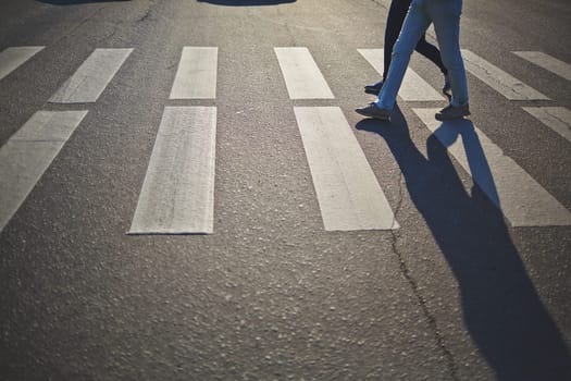 Urban couple in jeans and sports shoes crossing road
