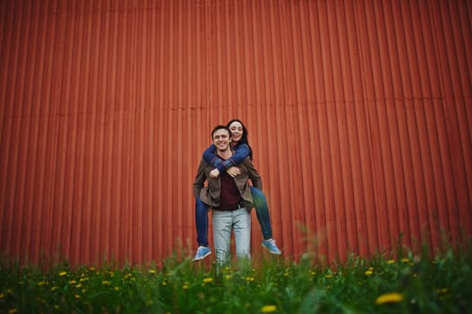 Cheerful couple standing on green lawn by wall