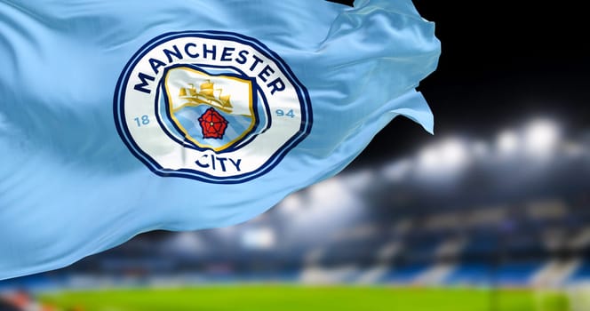 Manchester, UK, Nov 2022: Manchester City Football Club flag waving in the club stadium blurred in the background at night. Realistic 3d illustration. Illustrative editorial