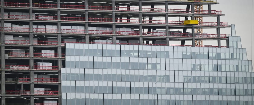Workers are actively engaged in the construction of a new high-rise building in Paris, highlighting a mix of glass elements and steel structure.
