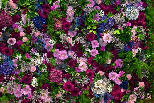 Lush floral display fills the backdrop with an exuberance of colors and textures, featuring diverse blooms and greenery, ideal for celebrations or decorative purposes.